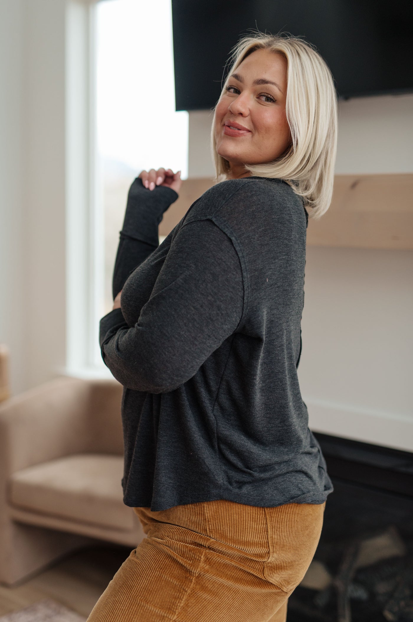 Made from a soft jersey knit, this top features exposed seams and a v-neckline that will flatter any figure. The thumb holes in the sleeve cuffs add an extra layer of warmth and style.