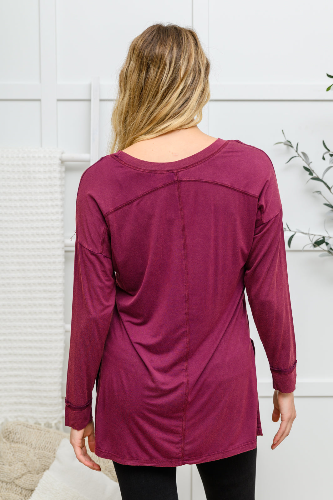 The Long Sleeve Knit Top With Pocket In Burgundy features a lightweight, stretchy fabric that shapes a round neckline with long sleeves, and a hi-low hem with side slits.
