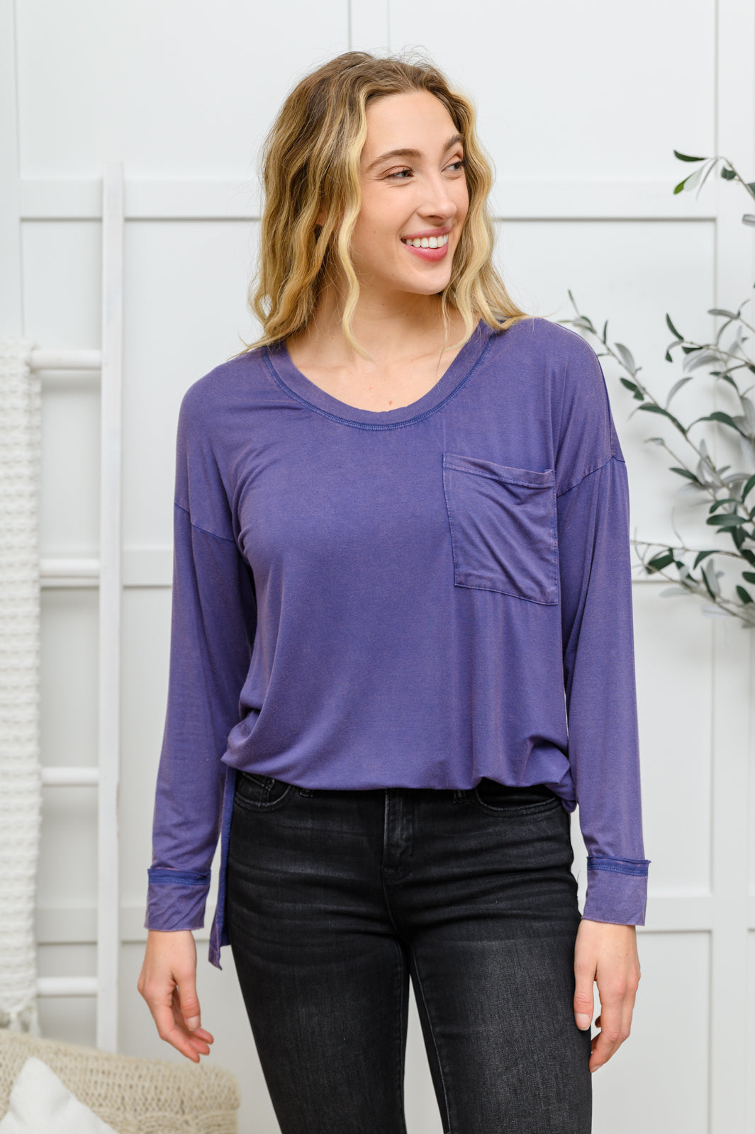 The Long Sleeve Knit Top With Pocket In Denim Blue features a lightweight, stretchy fabric that shapes a round neckline with long sleeves, and a hi-low hem with side slit