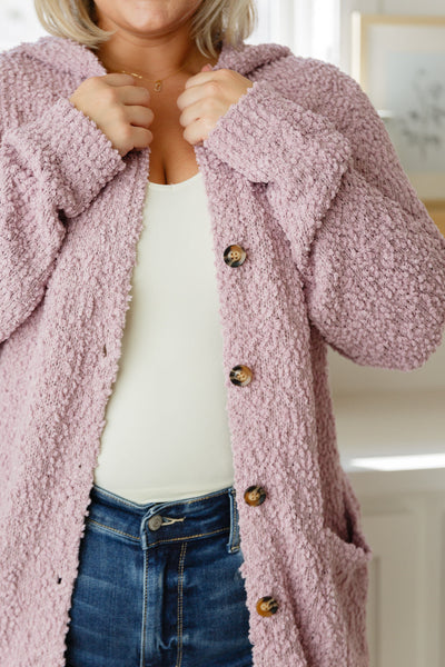 Crafted from a soft and luxurious boucle knit, this cardigan features a hooded design, button closure, front pockets, and an oversized fit for a look that's both chic and cozy