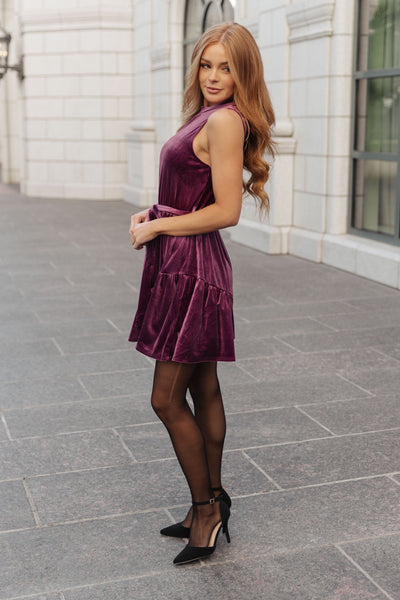 This luxurious velvet dress has a flattering mock neckline, sleeveless design, cased elastic waistband, and comes with a removable self-tie belt and ruffled hem for a chic, sophisticated look