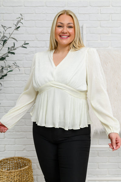 A stunning plisse fabric shapes a v neckline that drops into a peplum style waist, with long balloon sleeves, finished with a puff shoulder detail and elastic cuffs.